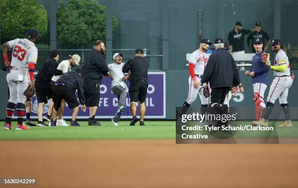 Fan yells to Ronald Acuna Jr. #13 of the Atlanta Braves after running on the field and being apprehended by security during the game between the...