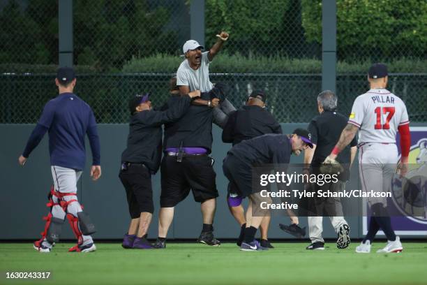 Fan yells to Ronald Acuna Jr. #13 of the Atlanta Braves after running onto the field and being apprehended by security during the game between the...