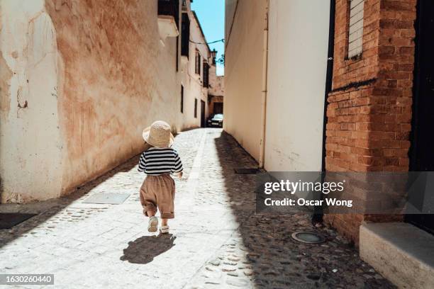 rear view of a little girl discovering street in the old town - narrow stockfoto's en -beelden