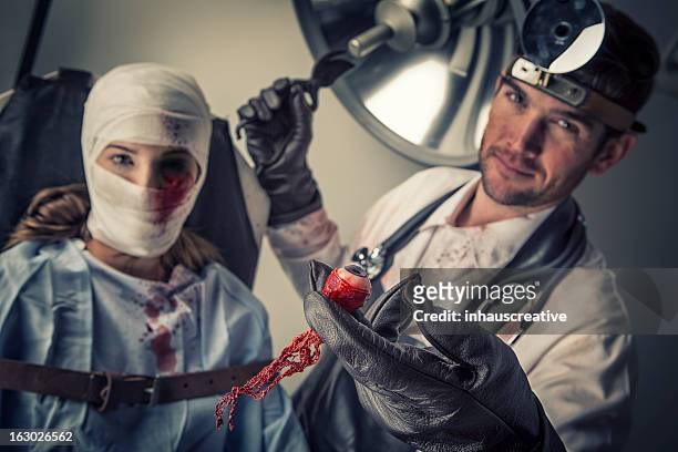evil doctor cutting out the eye of helpless female victim - evil doctor stock pictures, royalty-free photos & images