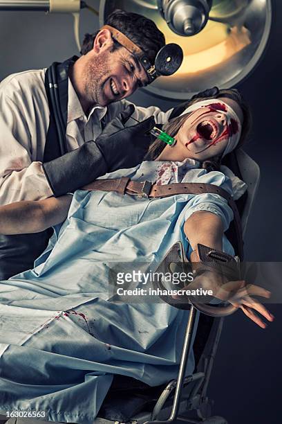 evil doctor trying out new serum on his female victim - evil doctor stock pictures, royalty-free photos & images