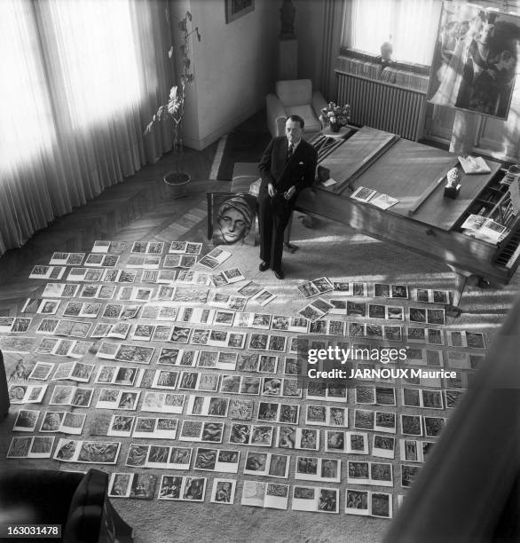 Andre Malraux At Home. Vue plongeante d'André MALRAUX debout dans le salon de sa maison de Boulogne-sur-Seine, appuyé au piano, devant des photos...