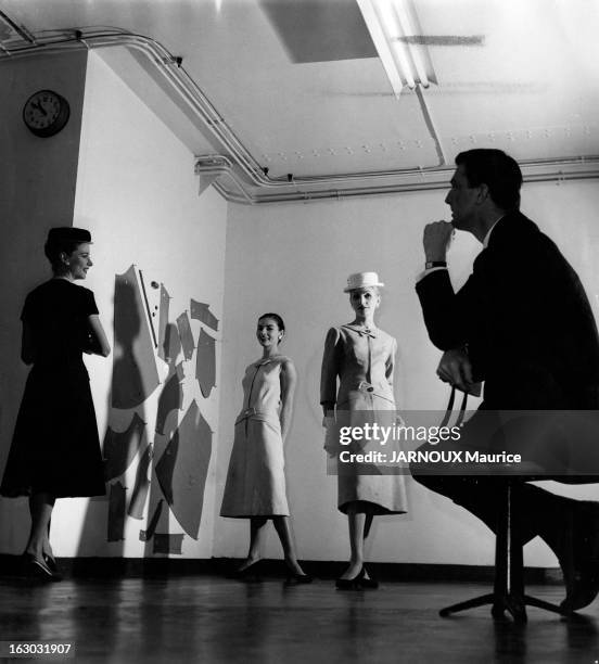 Hubert De Givenchy Launches His Pret-A-Porter. Attitude d'Hubert DE GIVENCHY de profil, assis sur un tabouret, regardant trois versions d'une de ses...