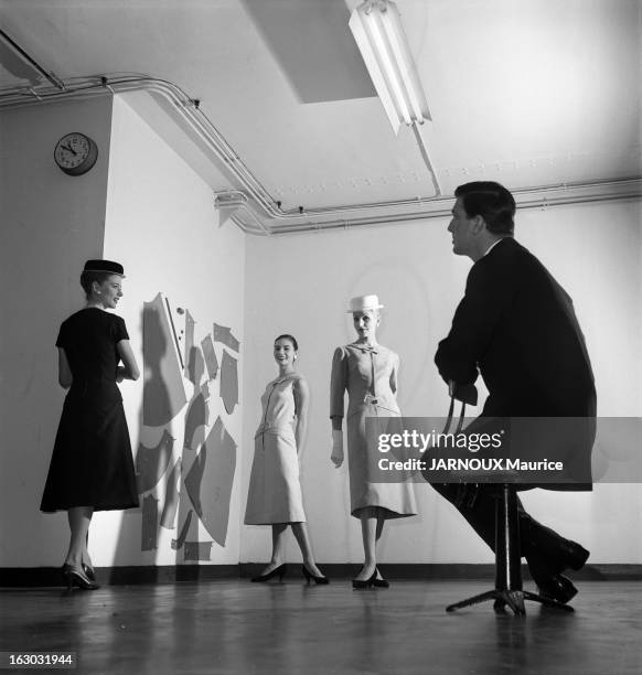 Hubert De Givenchy Launches His Pret-A-Porter. Attitude d'Hubert DE GIVENCHY de profil, assis sur un tabouret, regardant trois versions d'une de ses...