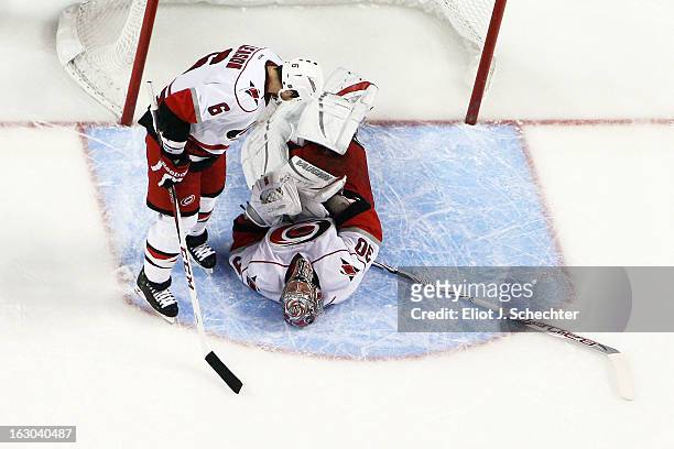 Goaltender Cam Ward of the Carolina Hurricanes lies on his back in pain while teammate Tim Gleason comes over to check on him against the Florida...