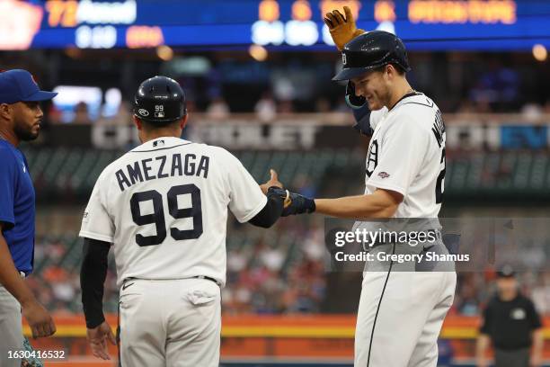 Parker Meadows of the Detroit Tigers celebrates his sixth inning single against the Chicago Cubs with first base coach Alfredo Amezaga at Comerica...