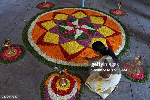 Woman devotee prepares Pookalam, a traditional floral arrangement, as she celebrates the 'Onam' festival at Ayyappa Temple in Hyderabad on August 29,...