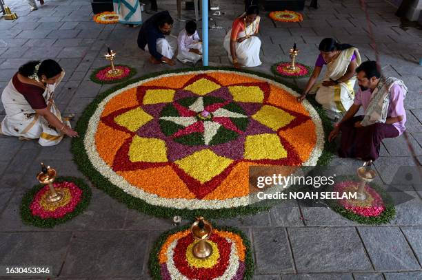 Devotees prepare Pookalam, a traditional floral arrangement, as they celebrate the 'Onam' festival at Ayyappa Temple in Hyderabad on August 29, 2023.