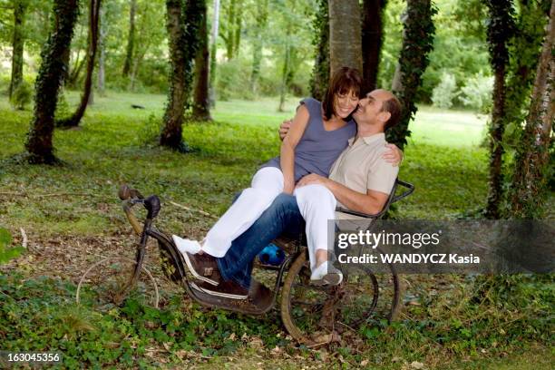 Rendezvous With Bernard Campan At Home. Anne sur les genoux de son mari Bernard CAMPAN assis sur un vieux tricycle dans le parc de leur propriété en...