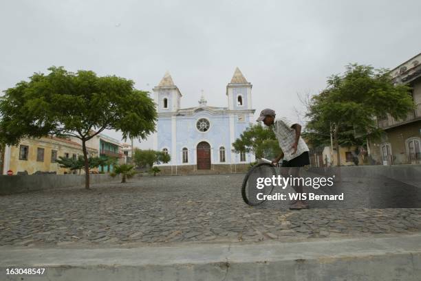 The Cape Verde Islands. Ile de Fogo : enfant jouant au cerceau avec une roue de vélo devant l'église adventiste de São Filipe.