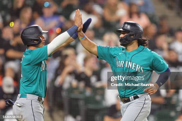 Josh Rojas and Eugenio Suarez of the Seattle Mariners celebrate after scoring a run on a two-run single by Teoscar Hernandez against the Chicago...