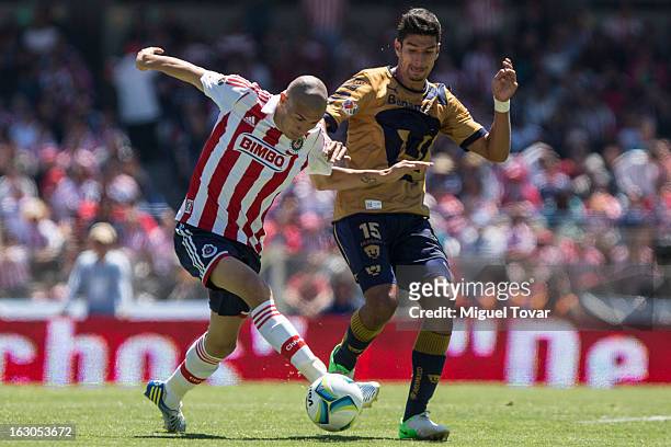 Eduardo Herrera of Pumas fights for the ball with Jorge Enriquez of Chivas during a match between Pumas and Chivas as part of the Clausura 2013 at...