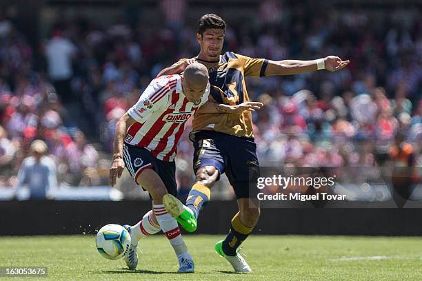 Eduerdo Herrera of Pumas fights for the ball with Jorge Enriquez of Chivas during a match between Pumas and Chivas as part of the Clausura 2013 at...