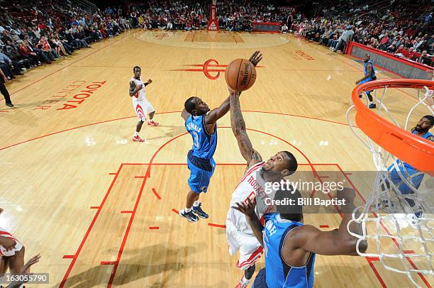 Thomas Robinson of the Houston Rockets grabs a rebound against Rodrigue Beaubois and Bernard James of the Dallas Mavericks on March 3, 2013 at the...