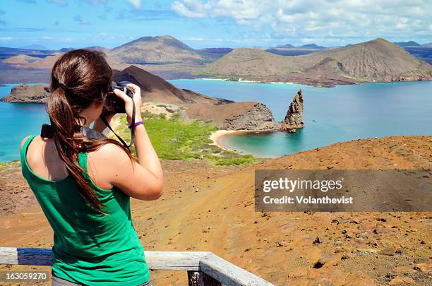 girl taking a picture of pinnacle rock, galapagos - galapagosinseln stock-fotos und bilder