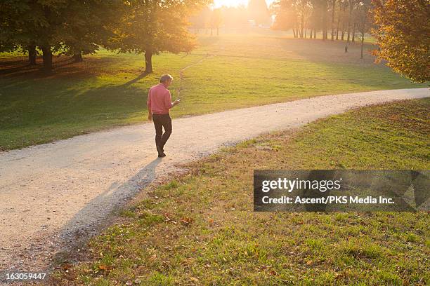 man walking along path thru park - man walking in a park stock pictures, royalty-free photos & images