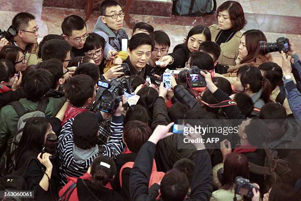 This picture taken on March 3, 2013 shows Chinese talk show host Cui Yongyuan surrounded by journalists and photographers as he attends the opening...