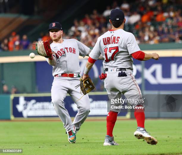 Alex Verdugo of the Boston Red Sox drops the ball after nearly colliding with Luis Urias in the sixth inning on a pop fly by Yainer Diaz of the...