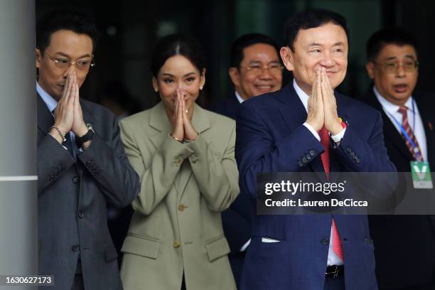 Former Thai prime minister Thaksin Shinawatra greets supporters next to his daughter Pintongtha Kunakornwong as he arrives at Don Mueang...