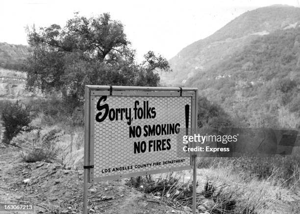 Sign on the side of a road states No Smoking from the Los Angeles Fire Department, 1955.