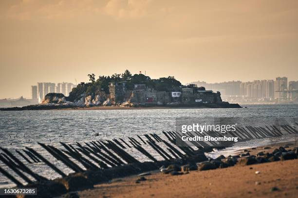 Dadan Island and buildings in Xiamen on mainland China stand across the Taiwan Strait from anti-landing barriers on a beach in Kinmen, Taiwan, on...