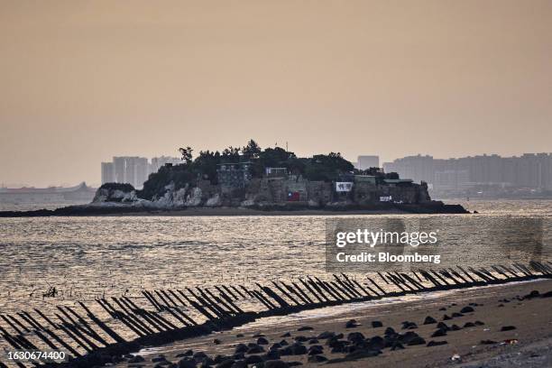 Dadan Island and buildings in Xiamen on mainland China stand across the Taiwan Strait from anti-landing barriers on a beach in Kinmen, Taiwan, on...