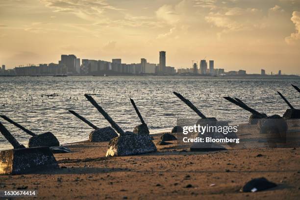Buildings in Xiamen on mainland China stand across the Taiwan Strait from anti-landing barriers on a beach in Kinmen, Taiwan, on Monday, Aug. 21,...