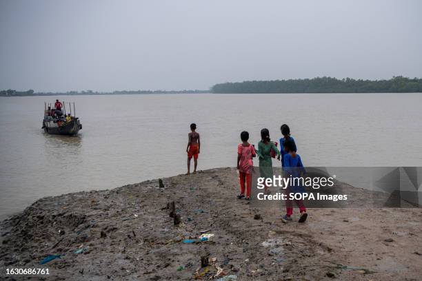 Children are seen waiting for a boat as they are on their way to school in a coastal area at Kalabogi in Khulna. Not too long ago, Kalabogi, a...