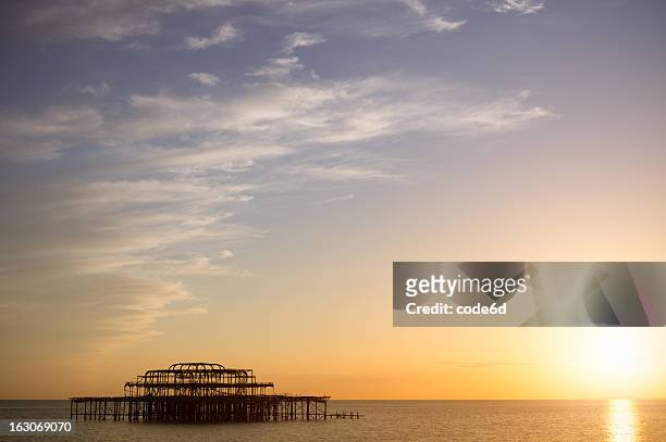 burnt brighton west pier at sunset - brighton beach stock pictures, royalty-free photos & images