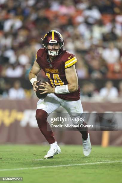 Sam Howell of the Washington Commanders scrambles and looks to pass against the Baltimore Ravens during an NFL preseason game at FedExField on August...