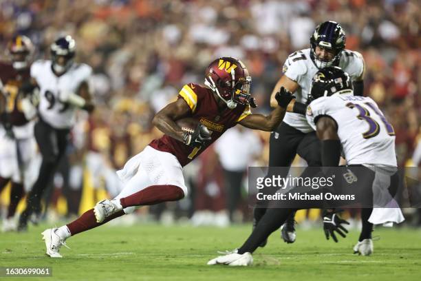 Jahan Dotson of the Washington Commanders runs with the ball against Jeremy Lucien of the Baltimore Ravens during an NFL preseason game at FedExField...