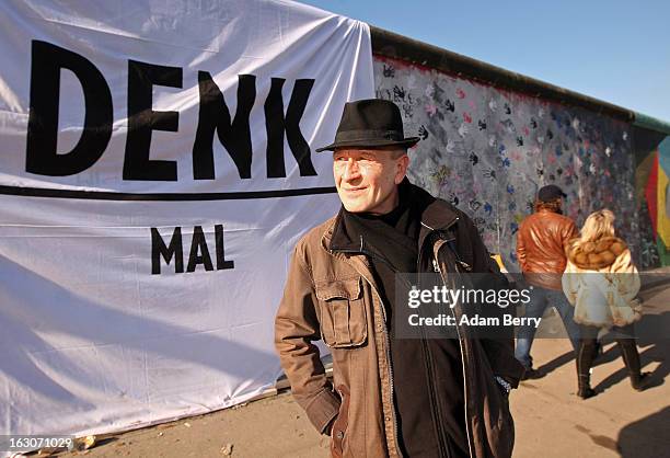 Artist Guenther Schaeffer, who has painted a section of the East Side Gallery, poses in front of a banner reading "Denk Mal," a pun in German on the...