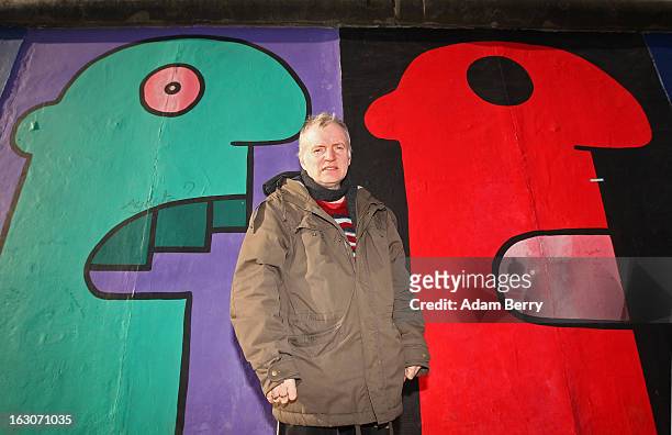 Artist Thierry Noir, who has painted a section of the East Side Gallery, poses in front of one of his murals painted on the longest remaining portion...