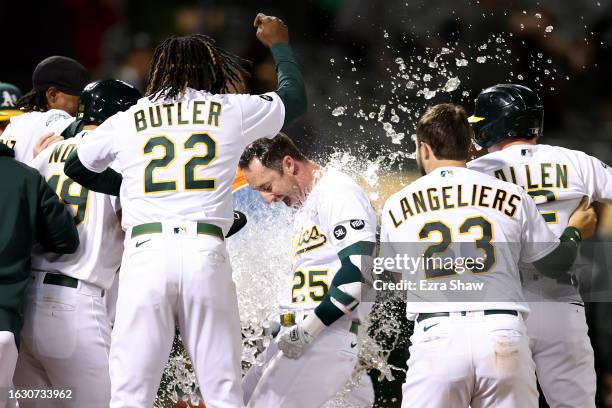 Brent Rooker of the Oakland Athletics is congratulated by teammates after he hit a two-run home run in the ninth inning to beat the Kansas City...