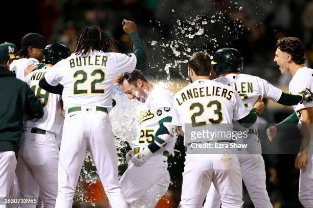 Brent Rooker of the Oakland Athletics is congratulated by teammates after he hit a two-run home run in the ninth inning to beat the Kansas City...
