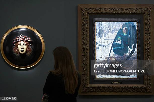 Woman looks at "La mort et le fossoyeur" by Carlos Schwabe and "Bouclier avec le visage de meduse" by Arnold Bocklin during the exhibition "The Angel...