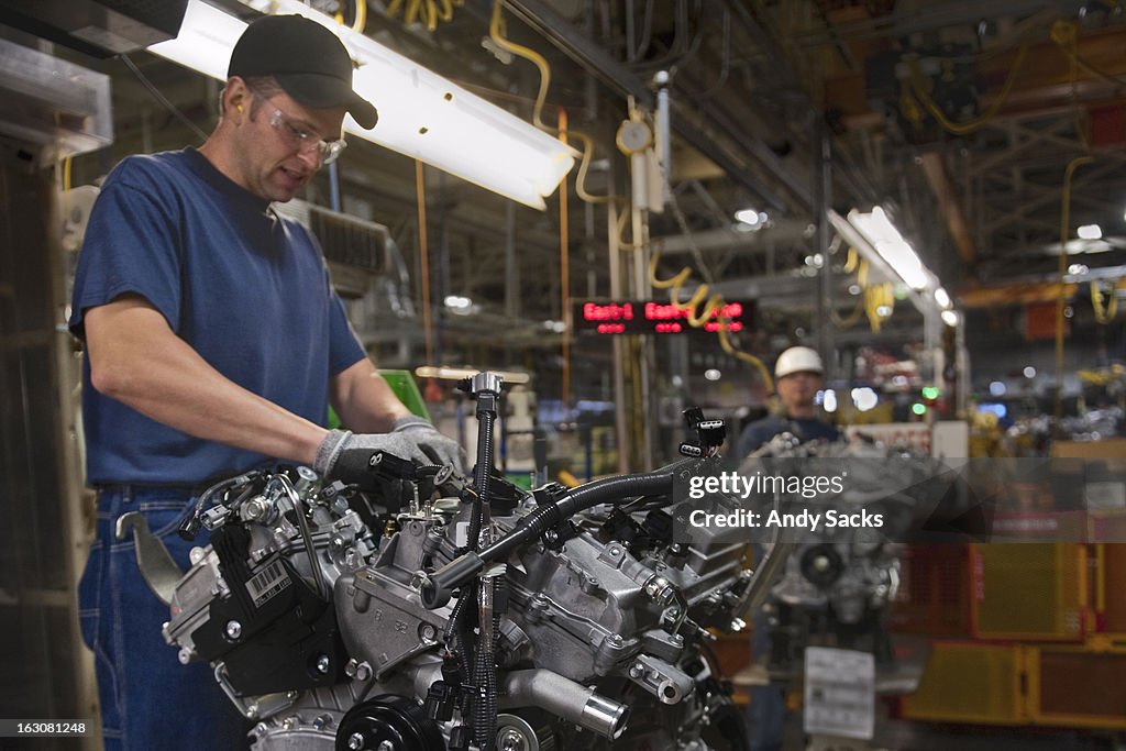 A worker attaches components to an auto engine