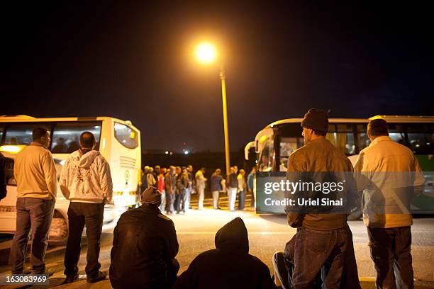 Palestinians wait to board a bus as a new line is made available by Israel to take Palestinian labourers from the Israeli army crossing of Eyal, near...