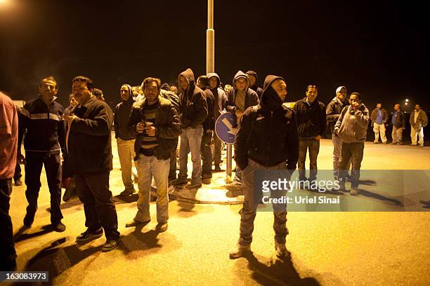 Palestinians wait to board a bus as a new line is made available by Israel to take Palestinian labourers from the Israeli army crossing of Eyal, near...