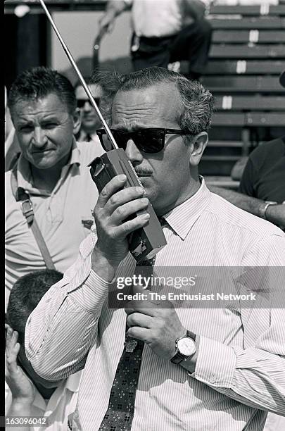 Indianapolis 500. Lotus founder Colin Chapman stands in pit lane talking on a 2-way radio.