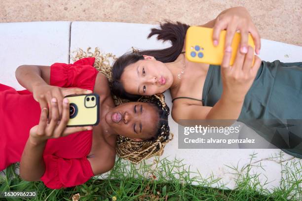 multi-ethnic friends taking selfies lying on a park - asian lesbians kiss stock pictures, royalty-free photos & images