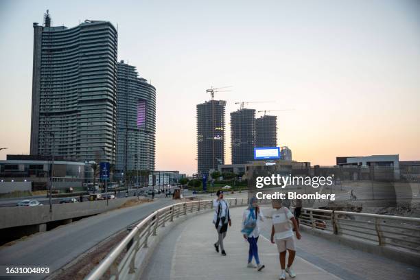 Visitors walk along a sidewalk in view of the Gate Towers and North Edge Towers high-rise residential developments in the New Alamein city...