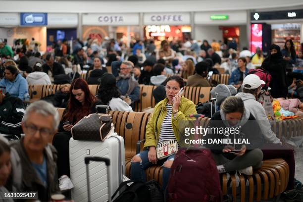 Passengers wait at Stansted Airport, north of London, on August 29, 2023 after UK flights were delayed over a technical issue. Flights to and from...