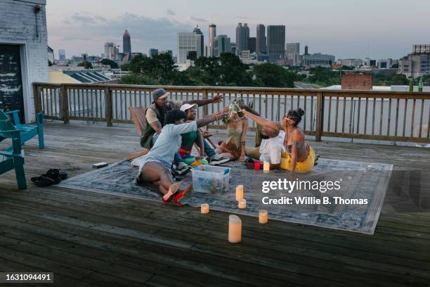 friends sitting on rug with candles during rooftop party - subculture stock pictures, royalty-free photos & images