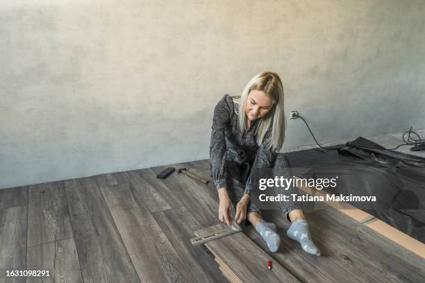 a young woman in a gray jumpsuit makes a modern renovation in a loft style. - new flooring stock pictures, royalty-free photos & images