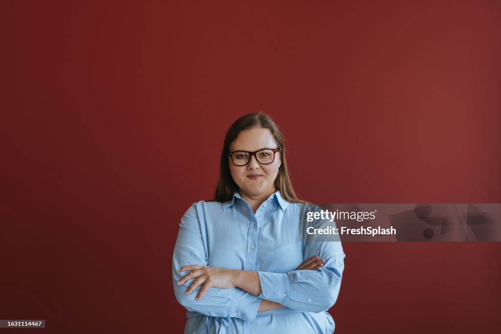 Portrait d’une femme d’affaires confiante de taille plus portant des lunettes avec les bras croisés