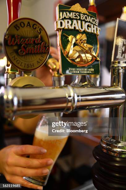 An employee pours a glass of Boag's Draught beer at the visitor's bar of the Boag's brewery, operated by Kirin Holdings Co.'s Lion unit, in...