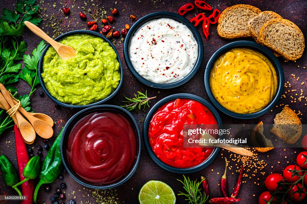 Ensemble de cinq sauces trempettes tirées d’en haut sur une table sombre