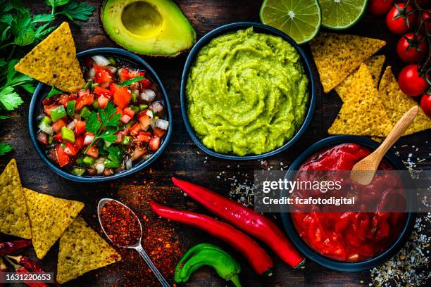 mexican food: salsa sauce, guacamole and pico de gallo with ingredients shot from above on dark table - mexican food stock pictures, royalty-free photos & images