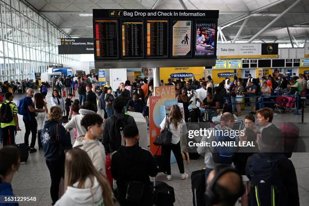 Passengers wait at Stansted Airport, north of London, on August 29, 2023 after UK flights were delayed over a technical issue. Flights to and from...